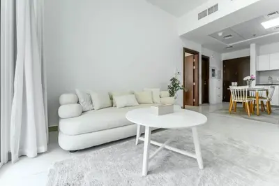 a white living room with a white couch and a table at FAM Living 1BR Stay Binghatti Gateway, Al Jaddaf in Dubai
