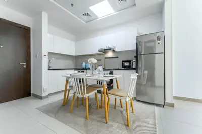 a kitchen with a table and chairs and a refrigerator at FAM Living 1BR Stay Binghatti Gateway, Al Jaddaf in Dubai