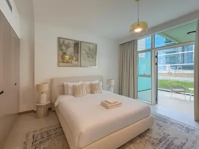 a white bedroom with a bed and a large window at Luxury Studio in Urban Oasis, Business Bay in Dubai
