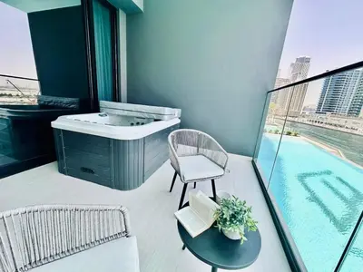 a bathroom with a sink and a chair and a table at Serene Canalfront Studio Apt With Private Jacuzzi! in Dubai