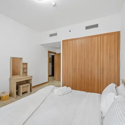 a bedroom with a large white bed with a wooden cabinet at 1BR in Sulafa Tower- Ideal for Short-Term Stay in Dubai