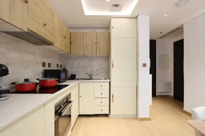 a kitchen with white cabinets and red pots on the stove at Stylish Studio with Spacious Balcony Walk to JBR Beach in Dubai