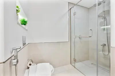a white bathroom with a shower and a toilet at Serene 1BR Stay with Pool, Gym, & Kids Playground in Dubai