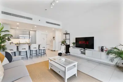 a living room with a couch and a tv at Serene 1BR Stay with Pool, Gym, & Kids Playground in Dubai