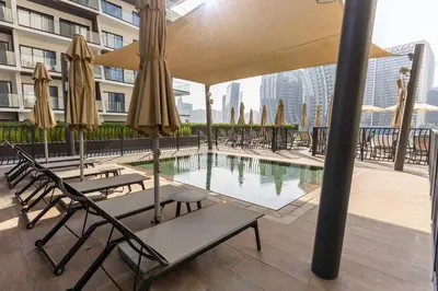 a pool with chairs and umbrellas on a building at Waves - Impressive 1BR Apartment Close to Burj Khalifa in Dubai