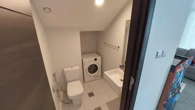 a small bathroom with a toilet and a washing machine at Damac hills 2 vardon cluster in Dubai