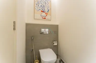 a bathroom with a toilet and a picture on the wall at Furnished 1BR, Walk to Business Bay Metro, Near Downtown, Ahad Residences, Business Bay by Deluxe Holiday Homes in Dubai