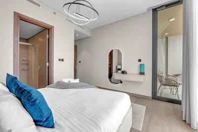 a bedroom with a large white bed and a chair at Relaxing 1BR w Maids room Minutes to Dubai Mall by Vibel in Dubai