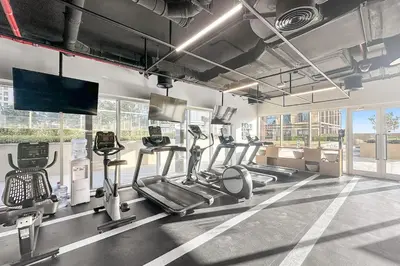 a gym with several tread machines and a flat screen tv at FIRST CLASS 1BR Modern Majesty in Dubai Hills in Dubai
