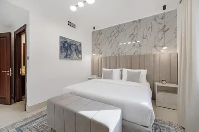 a white bedroom with a large white bed and a wall at Durrani Homes - Zaafaran Luxe Stay Iconic Burj View in Dubai