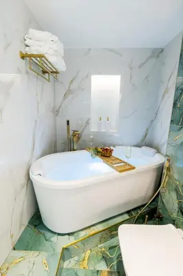 a bathroom with a white tub and marble walls at FIRST CLASS Studio Downtown Bliss Urban Gem in Dubai