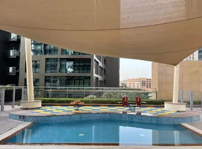 a swimming pool in a building with an umbrella at FIRST CLASS Studio Downtown Bliss Urban Gem in Dubai