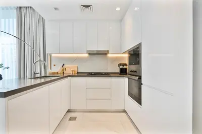 a white kitchen with white cabinets and a sink at Venetian - Relax in your private pool balcony in Dubai in Dubai