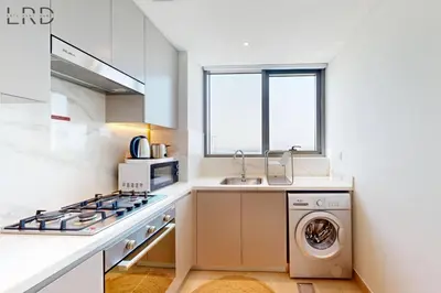 a kitchen with a stove and a washer and dryer at Chic 1BR with Canal View in Dubai