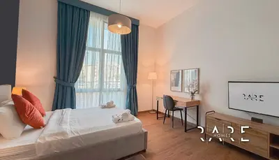a bedroom with a bed and a desk and a window at Rare Holiday Homes - Mediterranean Cluster - Near Ibn Battuta Mall - Discovery Garden - Building# Med 65 - RG04 in Dubai