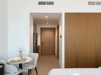 a room with a table and chairs and a room with a door at Cozy New Studio Heart of Al Furjan in Dubai