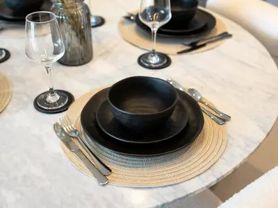 a table with a black cup and plates and wine glasses at Spacious, Modern Chic 2 BDR Apartment in Prime Downtown Location in Dubai