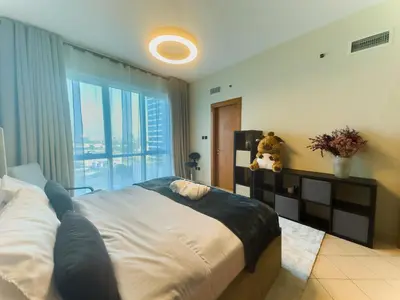 a bedroom with a large bed and a large window at Spacious 2BR in Lago Vista Tower in Dubai