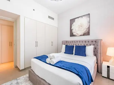 a bedroom with a large bed with blue pillows at Stylish Dubai Hills Retreat 1BR-Park Heights 2 T2 in Dubai