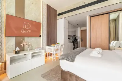 a bedroom with a large white bed and a kitchen at DAYF-LAV Brand New Apartment with Balcony in JVC in Dubai