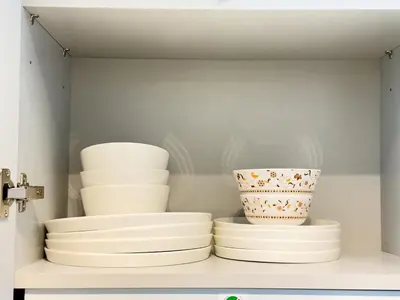 a shelf filled with white plates and vases at Stylish Studio Fast Wi-Fi 5 Min to Business Bay in Dubai