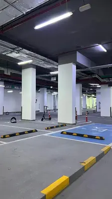 an empty parking lot with yellow and white pillars in a parking garage at Luxury Apartment in Binghatti Amber in Dubai