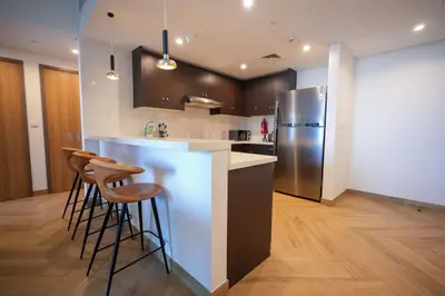 a kitchen with a bar with stools and a refrigerator at Modern 1BR 4 guest apartment World Trade Center in Dubai