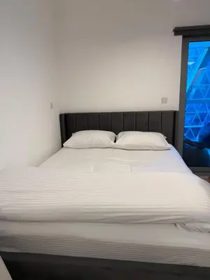 a large bed with white sheets and a window at Modern Studio in Damac Park Tower - Near Dubai Mall & Metro in Dubai