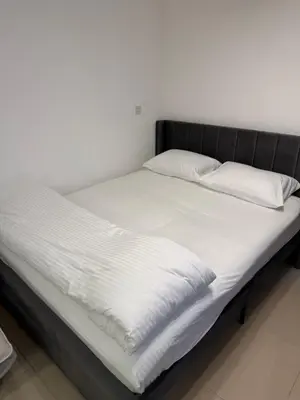 a bed with white sheets and pillows on it at Modern Studio in Damac Park Tower - Near Dubai Mall & Metro in Dubai