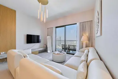 a living room with a white couch and a tv at FAM Living Grande 2Bed with Panoramic Burj Khalifa Fountain View in Dubai