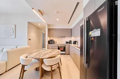 a small kitchen with a table and a refrigerator at FAM Living Grande 2Bed with Panoramic Burj Khalifa Fountain View in Dubai