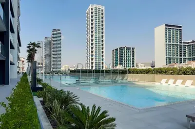 a large swimming pool in a city with tall buildings at High-Floor 1BR with Balcony Overlooking the Lake, Minutes from the Park, Binghatti Onyx, Jumeirah Village Circle by Deluxe Holiday Homes in Dubai