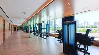 a gym with a row of exercise equipment in a building at High-Floor 1BR with Balcony Overlooking the Lake, Minutes from the Park, Binghatti Onyx, Jumeirah Village Circle by Deluxe Holiday Homes in Dubai