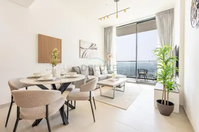 a white living room with a dining room table and chairs at High-Floor 1BR with Balcony Overlooking the Lake, Minutes from the Park, Binghatti Onyx, Jumeirah Village Circle by Deluxe Holiday Homes in Dubai
