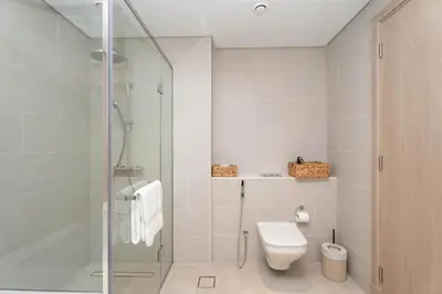 a bathroom with a toilet and a glass shower at Luxury 3BR & Maid - Canal View - Near Downtown in Dubai