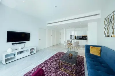 a living room with a blue couch and a tv at Designer 1BR Retreat With Stunning Canal View in Dubai