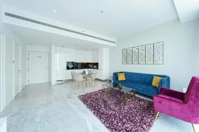 a living room with a blue couch and a purple rug at Designer 1BR Retreat With Stunning Canal View in Dubai