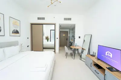 a bedroom with a bed and a tv and a table at AWS Holiday Homes - Relaxing Stylish Studio in Dubai