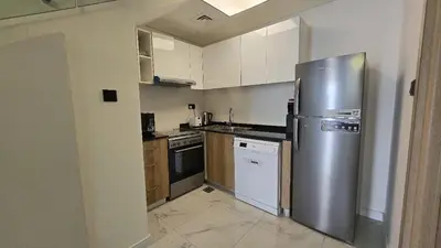 a kitchen with a stainless steel refrigerator and wooden cabinets at Stylish 1BR Loft TH in Rukan in Dubai