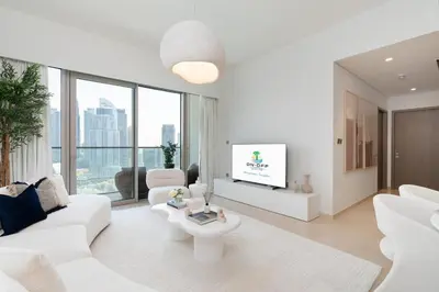 a white living room with a white couch and a tv at Grande, Luxurious 2 BR, Burj Khalifa & Fountain view in Dubai