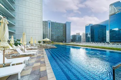 a swimming pool with chairs and umbrellas on a building at High-Rise 2BR with Dubai Water Canal View, Quick Access to Downtown, Vera Tower, Business Bay by Deluxe Holiday Homes in Dubai