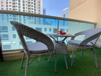 three chairs and a table on a balcony at Stunning 1Bedroom Apartment 5 min walking distance Metro and JBR Beach in Dubai