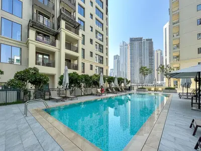a swimming pool with chairs and umbrellas next to buildings at Elegant at Creek Beach Lotus 1BHK in Dubai