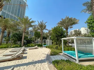 a beach with chaise lounge chairs and palm trees at Elegant at Creek Beach Lotus 1BHK in Dubai