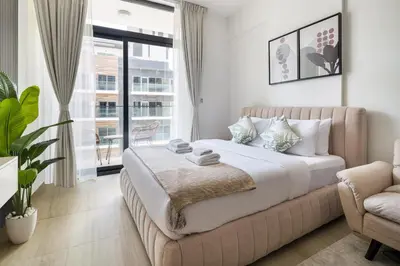 a bedroom with a bed and a couch and a window at Luxurious JVC Studio Near Circle Mall & Parks in Dubai
