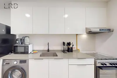 a white kitchen with a sink and a washing machine at Chic and Aesthetic Studio! Move-In Ready in Dubai