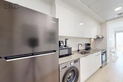 a kitchen with a stainless steel refrigerator and a dishwasher at Chic and Aesthetic Studio! Move-In Ready in Dubai
