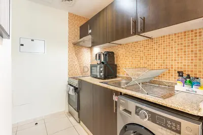 a kitchen with a sink and a dishwasher at Studio with Balcony Facing the Community, Located Near Golf Clubs and Cricket Stadium, Royale Residence 1 , Dubai Sports City by Deluxe Holiday Homes in Dubai