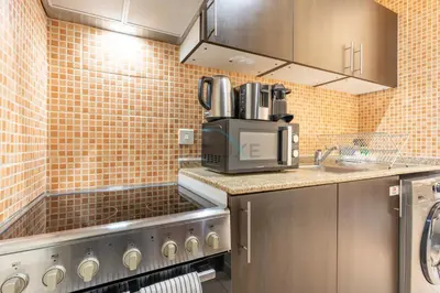 a kitchen with a sink and a microwave at Studio with Balcony Facing the Community, Located Near Golf Clubs and Cricket Stadium, Royale Residence 1 , Dubai Sports City by Deluxe Holiday Homes in Dubai