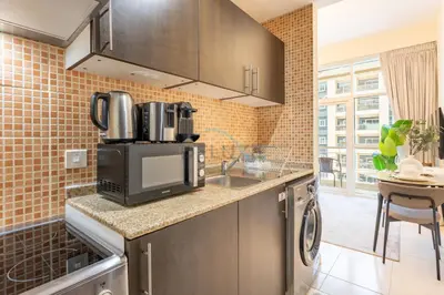 a kitchen with a sink and a microwave at Studio with Balcony Facing the Community, Located Near Golf Clubs and Cricket Stadium, Royale Residence 1 , Dubai Sports City by Deluxe Holiday Homes in Dubai